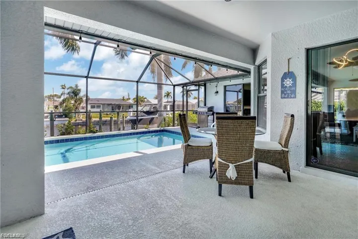 Swimming pool with a sunroom, a patio area, a lanai, area for grilling, and a residential view