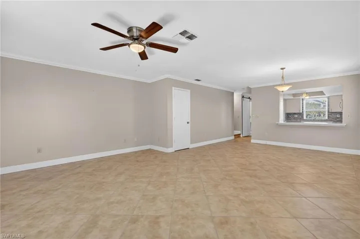 Empty room featuring ornamental molding, a ceiling fan, and light tile patterned floors