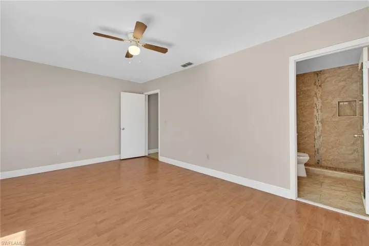 Unfurnished bedroom featuring a ceiling fan, light wood-style flooring, and ensuite bath