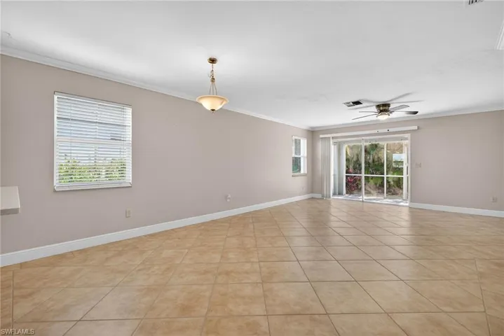 Empty room with ornamental molding, light tile patterned flooring, and ceiling fan