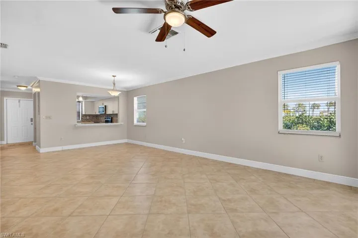 Unfurnished living room with crown molding, a ceiling fan, and light tile patterned flooring