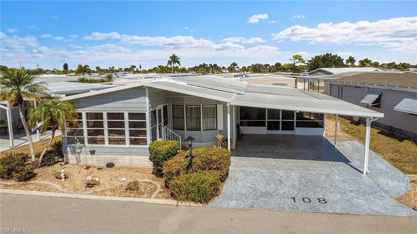 View of front of property featuring a carport, driveway, and a sunroom