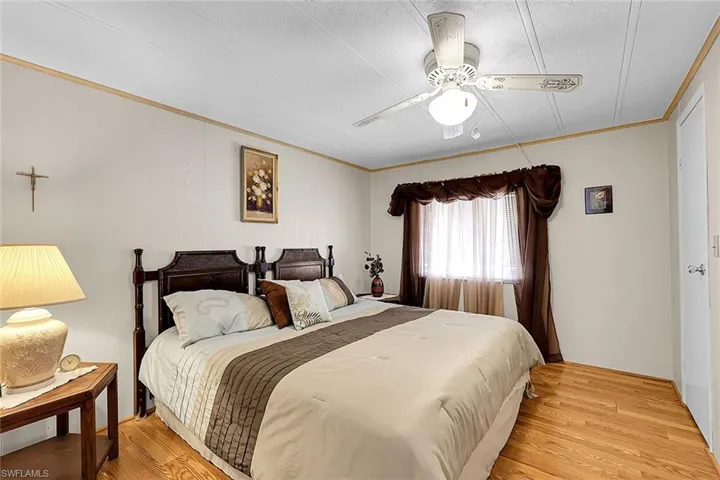 Bedroom with light wood-type flooring, a ceiling fan, ornamental molding, and a textured ceiling