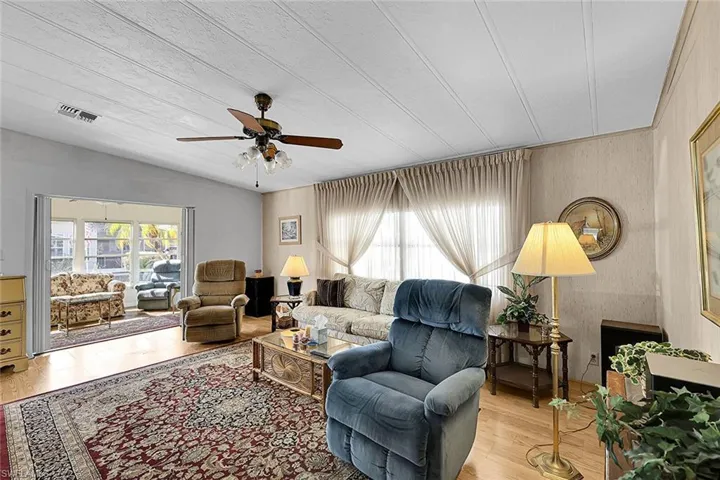 Living room featuring wood finished floors, a ceiling fan, and lofted ceiling