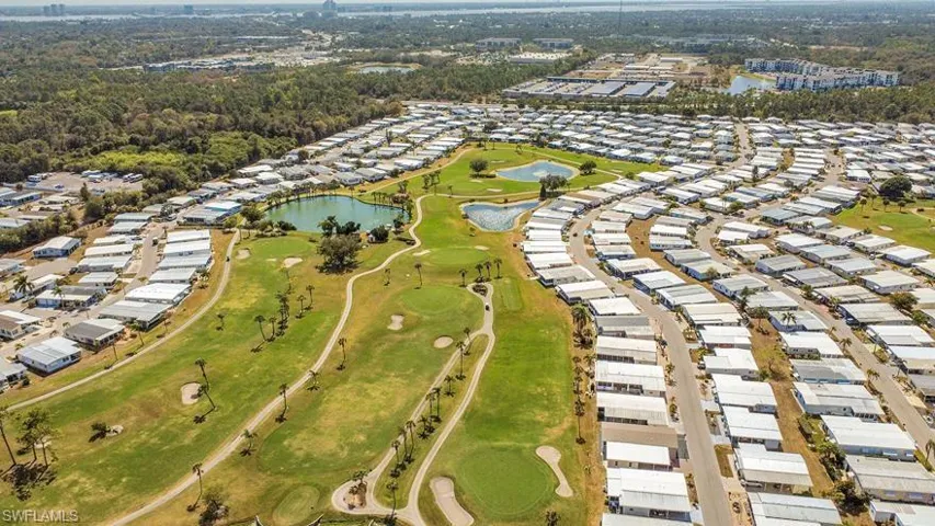 Aerial perspective of suburban area featuring a nearby body of water and a local golf course