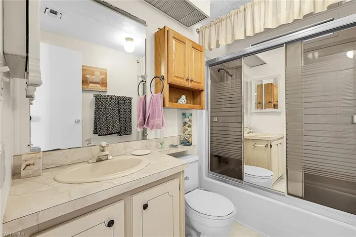 Bathroom with shower / bath combination with glass door and vanity