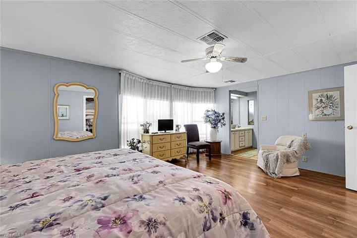 Bedroom with wood finished floors, ceiling fan, and ensuite bathroom