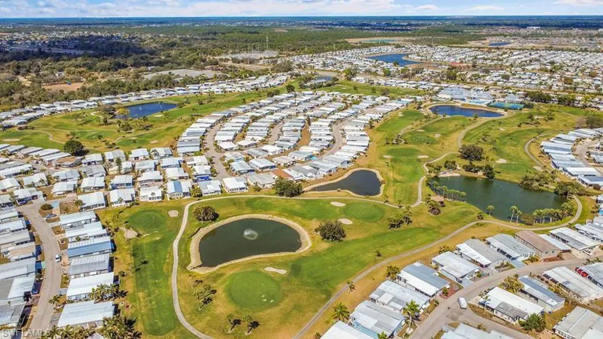 Aerial view of residential area featuring a nearby body of water and a golf club