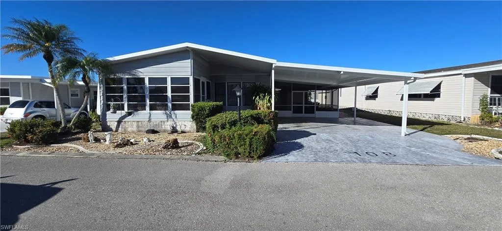 View of front of property featuring a sunroom, a carport, and driveway