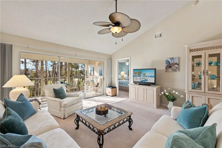 Living room with high vaulted ceiling, light carpet, a textured ceiling, and ceiling fan