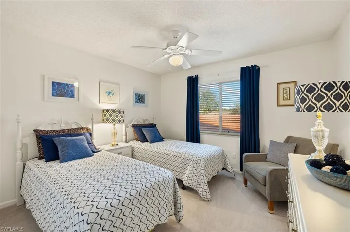Bedroom with ceiling fan, light colored carpet, and a textured ceiling