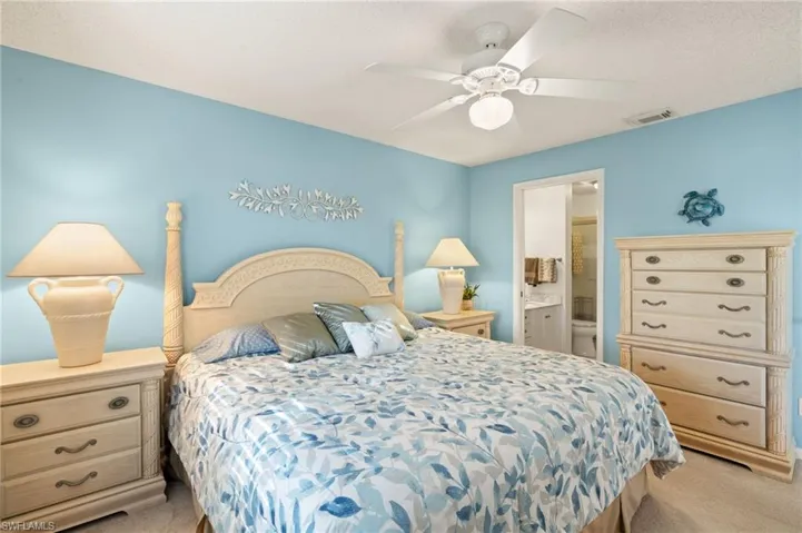 Carpeted bedroom with connected bathroom and ceiling fan