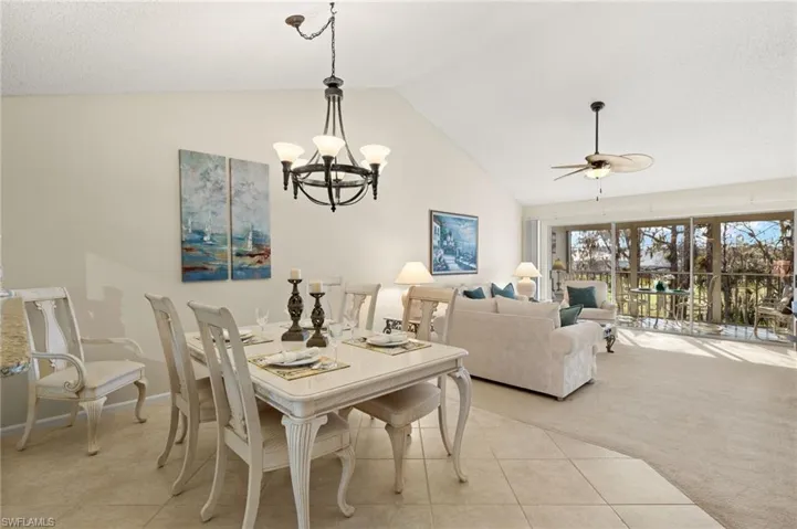 Carpeted dining area featuring high vaulted ceiling and ceiling fan