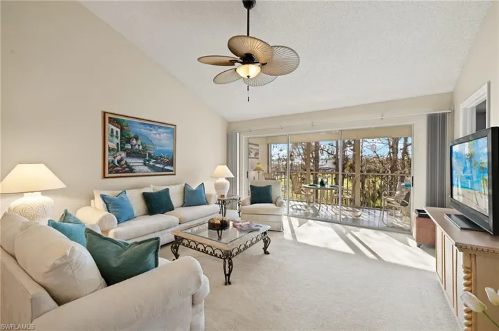 Living room featuring light carpet, a textured ceiling, high vaulted ceiling, and ceiling fan