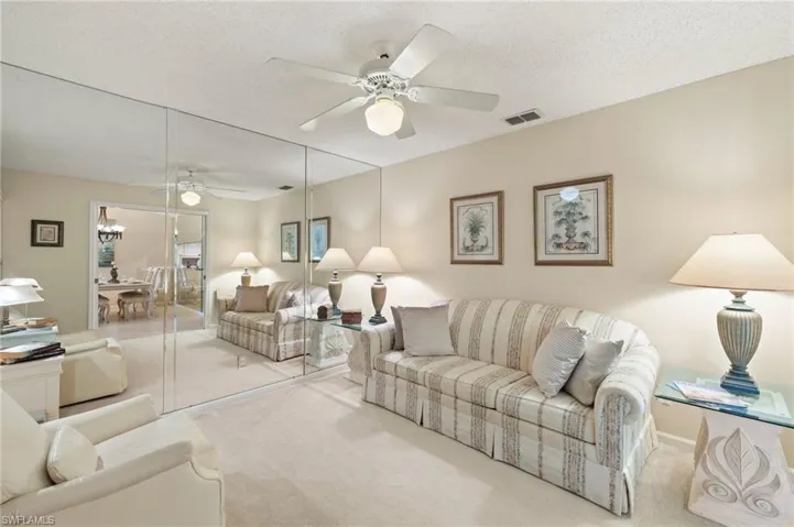 Living room with ceiling fan, light colored carpet, and a textured ceiling