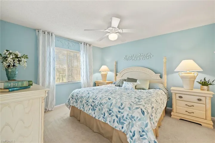Bedroom featuring ceiling fan, light colored carpet, and a textured ceiling