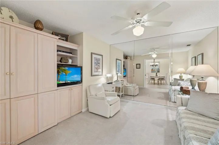 Carpeted living room featuring ceiling fan and a textured ceiling