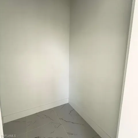 Unfurnished room with marble look tiles and baseboards