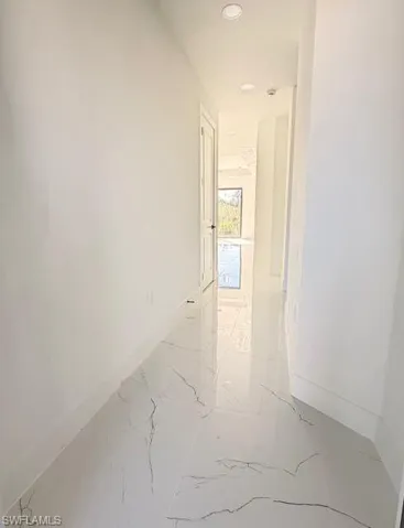 Hall featuring light marble finish flooring and recessed lighting
