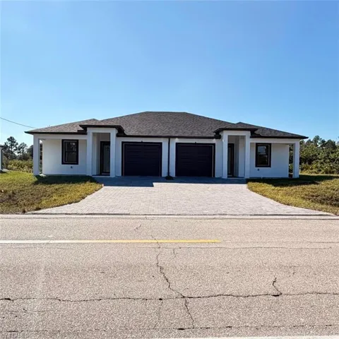 Prairie-style home with decorative driveway, an attached garage, roof with shingles, and a front yard