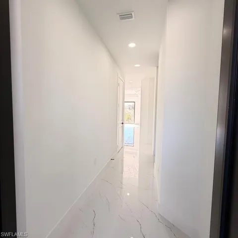 Hallway with recessed lighting and light marble finish floors