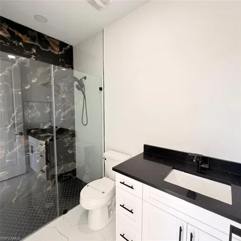 Full bathroom featuring vanity, a marble finish shower, and marble finish floors