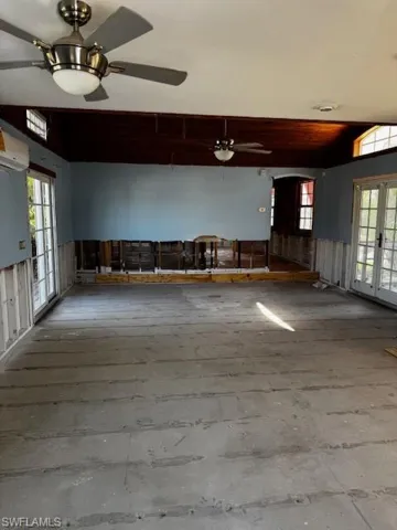 Spare room featuring arched walkways, french doors, vaulted ceiling, and a ceiling fan