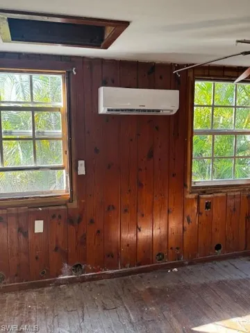 Empty room featuring an AC wall unit, a healthy amount of sunlight, and hardwood / wood-style flooring