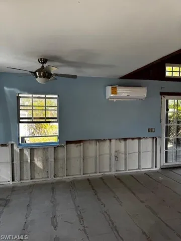 Empty room featuring a wall mounted AC and a ceiling fan