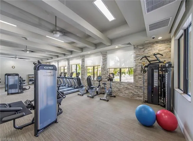 Gym with beamed ceiling and ceiling fan