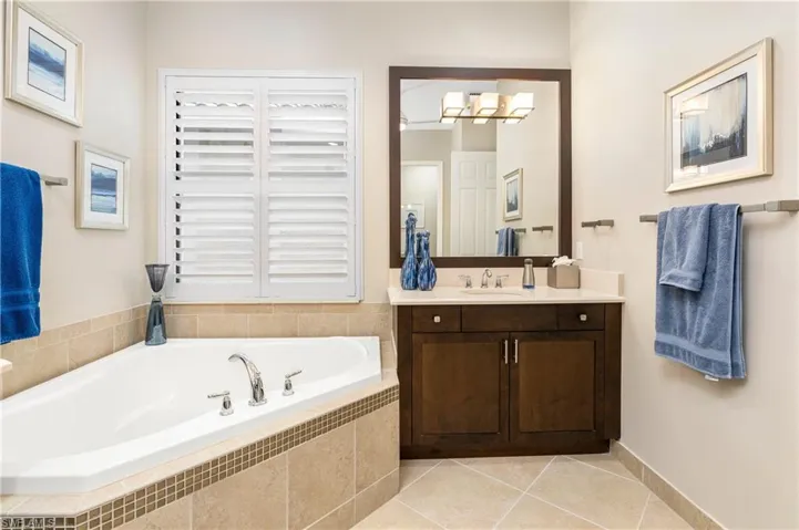 Full bath featuring a garden tub, vanity, light tile patterned floors, and a chandelier