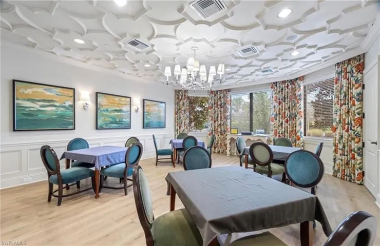 Dining space with ornamental molding, coffered ceiling, a chandelier, light wood-style floors, and a decorative wall