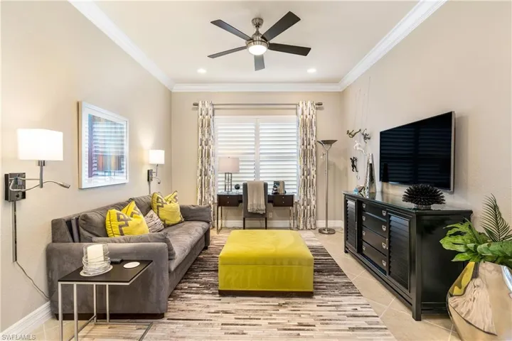 Living room with crown molding, light tile patterned floors, and a ceiling fan