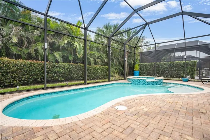 View of pool with a pool with connected hot tub, a sunroom, glass enclosure, and a patio