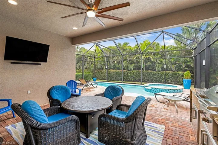 View of patio / terrace featuring a sunroom, a pool with connected hot tub, a ceiling fan, a lanai, and grilling area