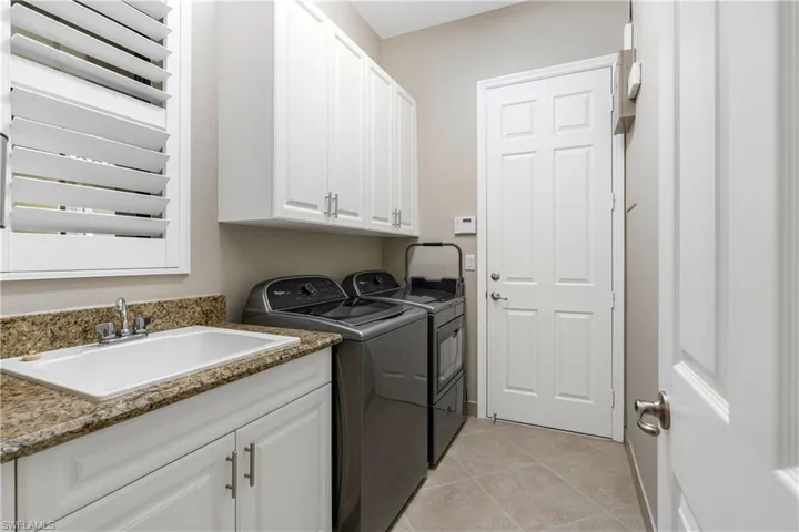 Washroom featuring light tile patterned flooring, cabinet space, and washer and clothes dryer