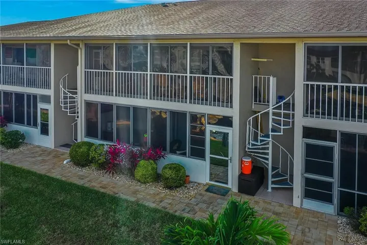 Rear view of property featuring stairs, a balcony, a shingled roof, and a sunroom