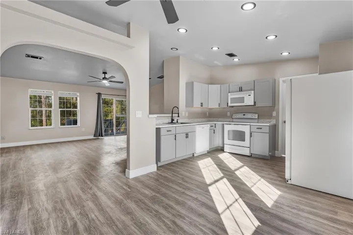 Kitchen with white appliances, light countertops, open floor plan, light wood-style flooring, and recessed lighting