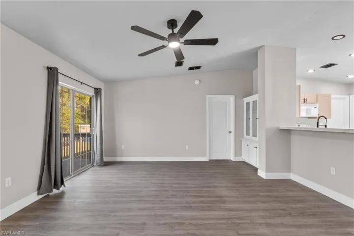 Unfurnished living room featuring dark wood finished floors, a ceiling fan, and vaulted ceiling