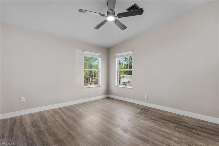 Spare room with wood finished floors, lofted ceiling, and a ceiling fan