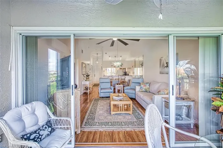 Living area with a textured wall, wood finished floors, and a ceiling fan