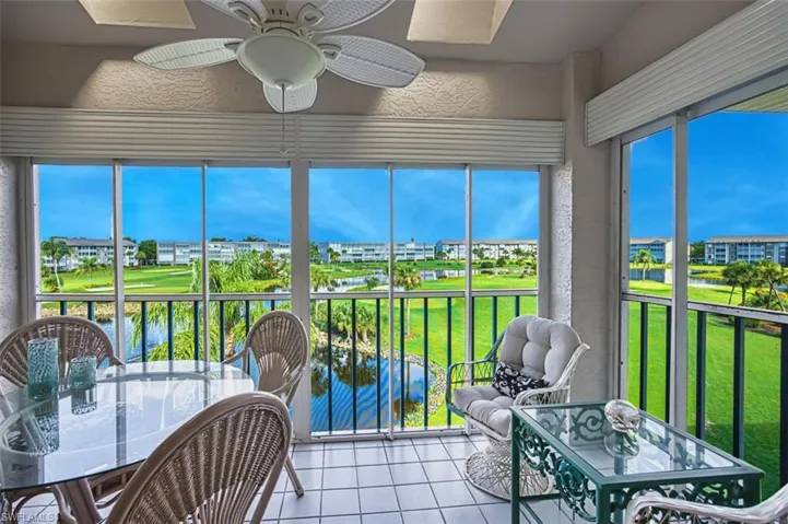 Sunroom featuring a ceiling fan, tile patterned flooring, outdoor dining space, a water view, and a textured wall