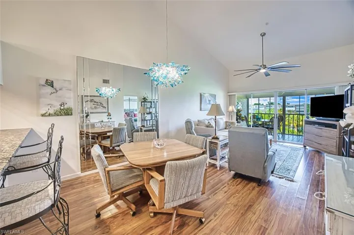 Dining space featuring wood finished floors, high vaulted ceiling, and a ceiling fan