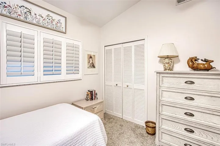 Carpeted bedroom with a closet and vaulted ceiling