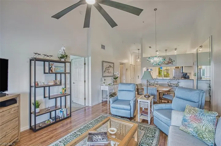 Living room with high vaulted ceiling, wood finished floors, and a ceiling fan