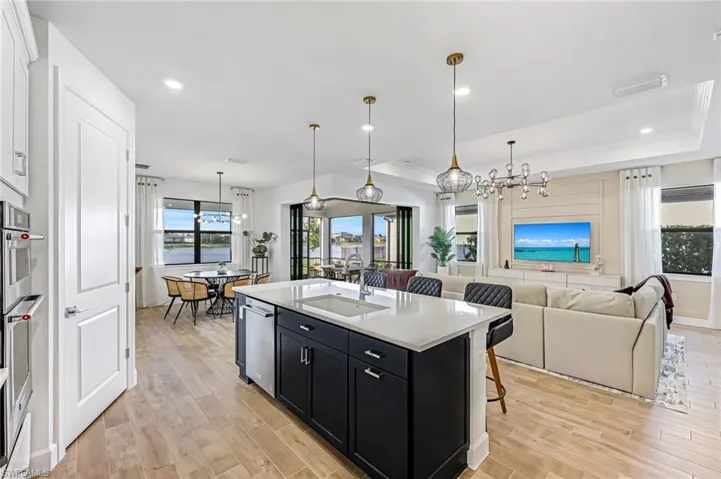 Kitchen featuring dark cabinetry, a kitchen breakfast bar, pendant lighting, light wood-style flooring, and recessed lighting