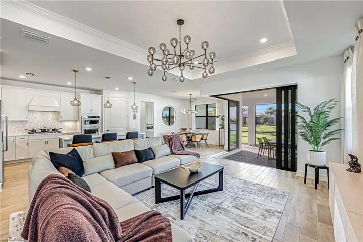 Living room with a chandelier, light wood-style flooring, recessed lighting, and crown molding