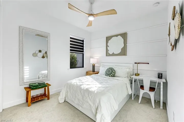 Carpeted bedroom with ceiling fan and baseboards
