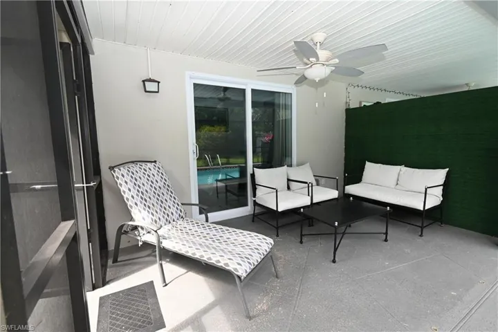 Covered outdoor patio featuring a slatted ceiling, ceiling fan, and a sliding glass door providing access to the pool area