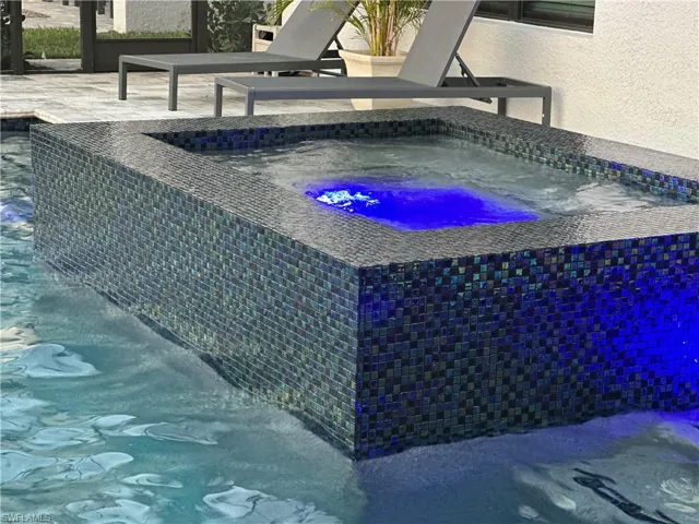 View of 360 waterfall spa and tile wall feature with color changing pool lighting